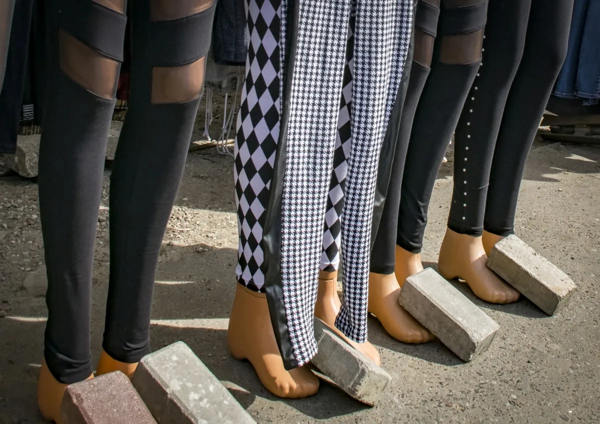 Row of mannequin legs weighted down with concrete blocks